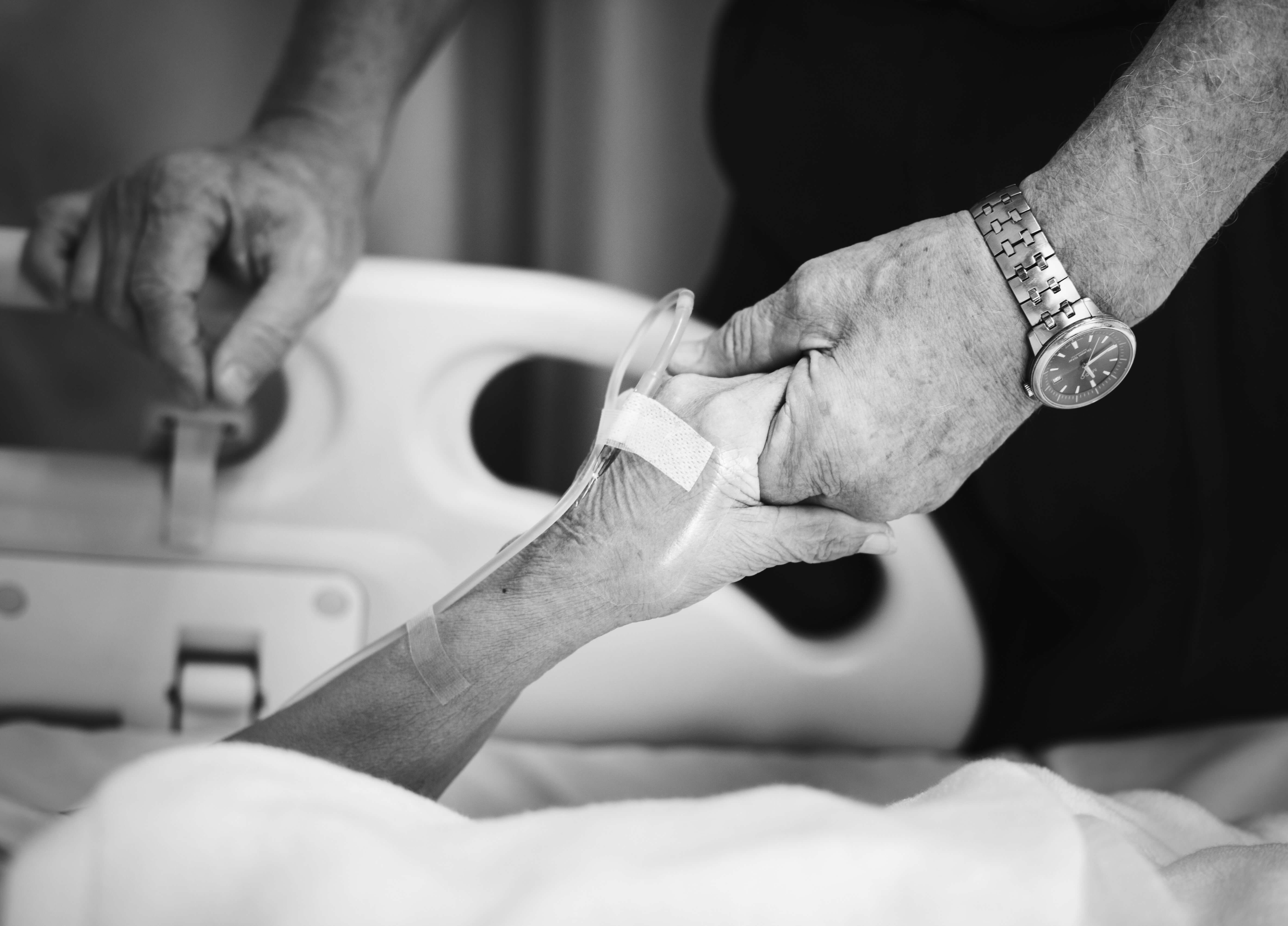 Nurse holds a patients hand in black and white.