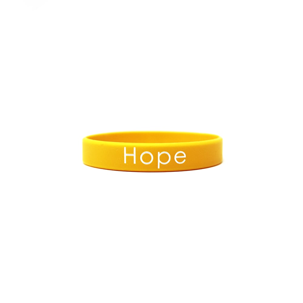 A yellow engraved wristband that says hope.